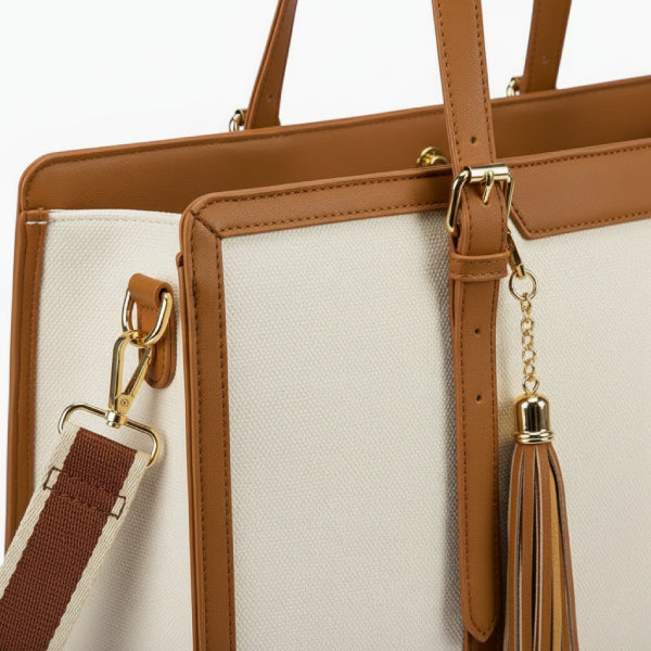 Close-up of Clea off-white polyester tote bag showcasing the leather handles, gold hardware, and tassel detail