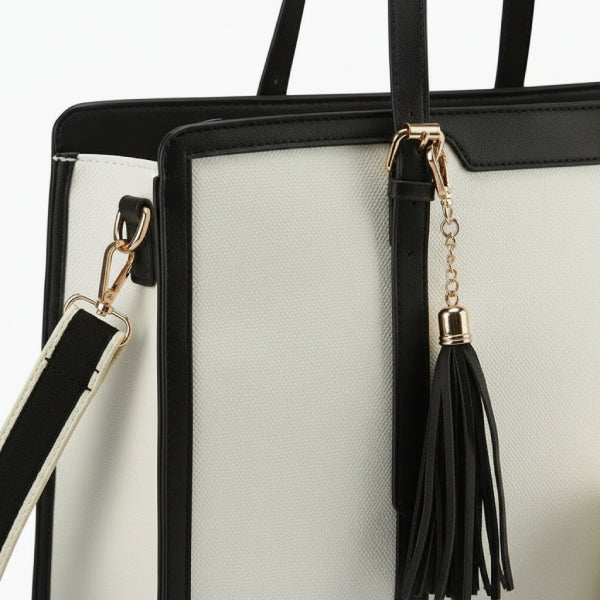 Close-up view of Clea duo set polyester tote bag showing the gold zipper and black tassel detail on the white and black bag