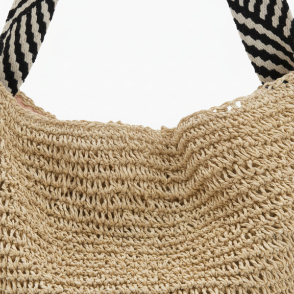 Close-up of beige woven tote bag showing textured material and striped handles for a chic look