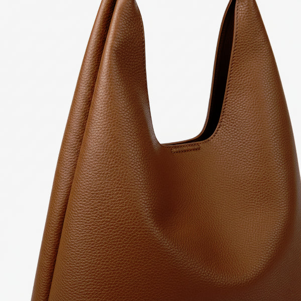 Close-up of Elaria vegan leather hobo bag in brown, featuring a textured pebbled surface and a sleek, slouchy design with a smooth handle