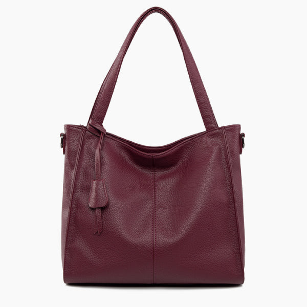 Front view of the wine red vegan leather tote bag featuring a minimalist design with a central tassel detail and elegant handles