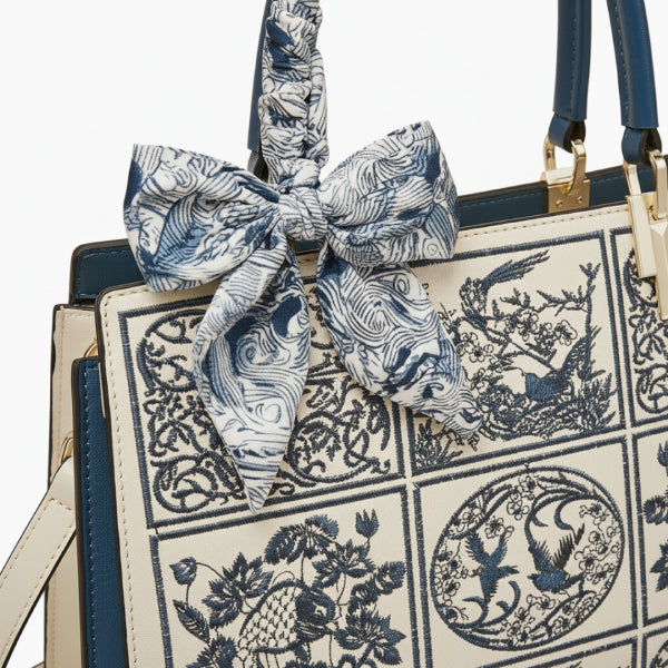Close-up of the Elisandra embroidered tote bag featuring a detailed floral design with a decorative blue bow attached to the handle