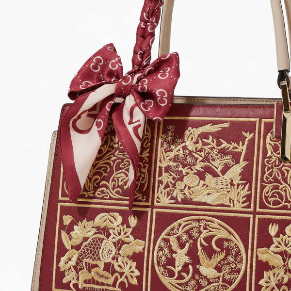 Close-up of the off-red Elisandra embroidered tote bag, featuring intricate floral patterns and a decorative bow tied to the handle
