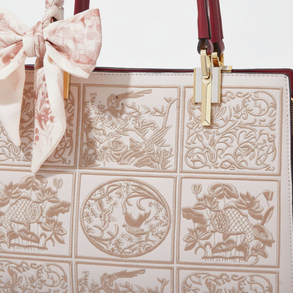 Close-up of the off-white Elisandra embroidered tote bag, focusing on the intricate floral embroidery and the decorative bow attached to the handle