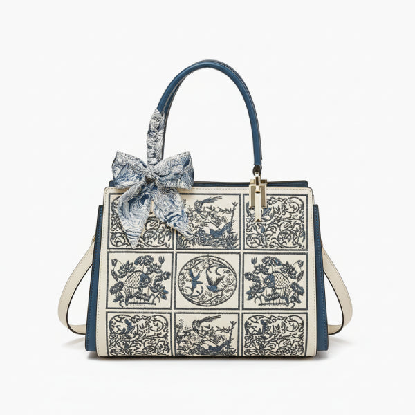 Front view of the Elisandra embroidered tote bag showcasing an intricate floral embroidery design with a stylish blue bow on the handle
