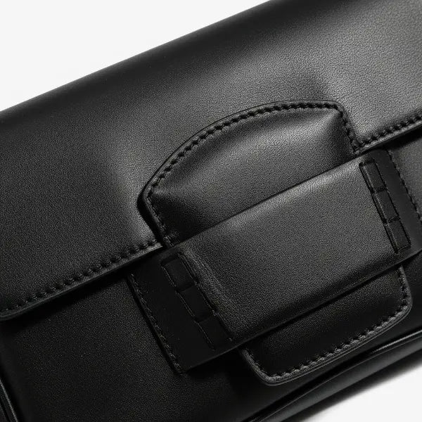Close-up of the Faelina genuine cowhide shoulder bag in black showcasing its sleek buckle closure and smooth leather texture