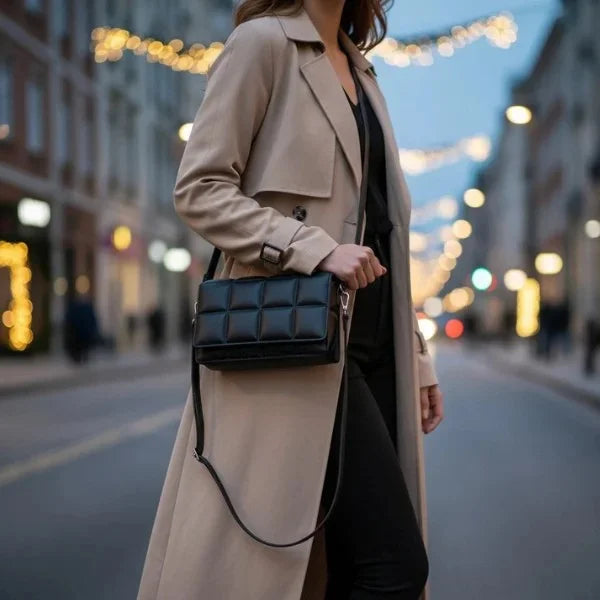Isla Vegan Leather Crossbody Bag in black, lifestyle street shot with model showing padded grid design and adjustable crossbody strap