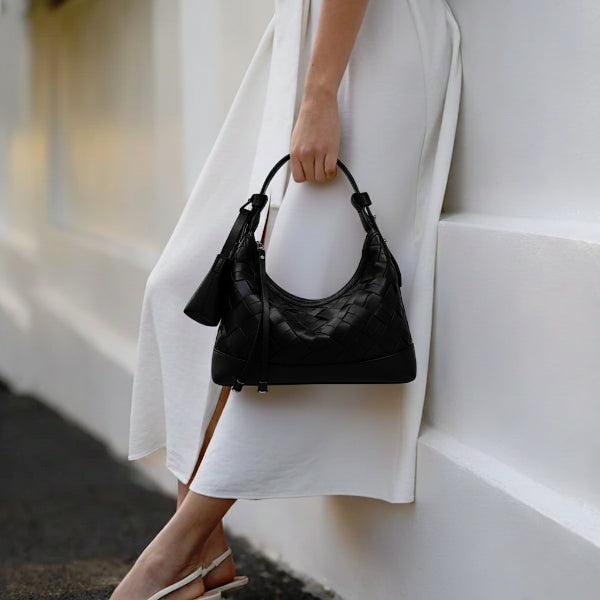 Model holding Ismara genuine leather woven hobo bag in black, featuring a woven texture and comfortable shoulder strap