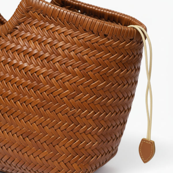 Close-up of a genuine leather brown tote bag with woven texture and beige drawstring closure