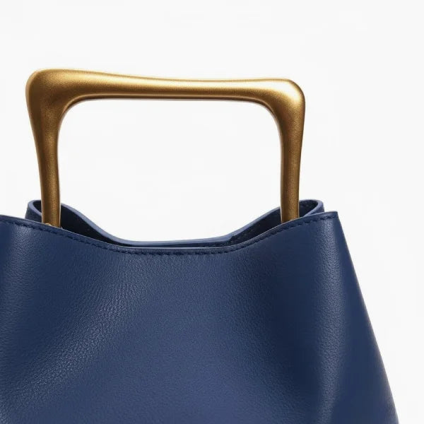 Close-up of a Blue Izelia top grain leather crossbody bag with a gold handle on a white background