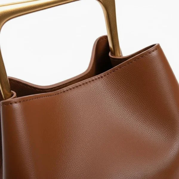 Close-up of a Brown Izelia top grain leather crossbody bag with gold handles on a white background