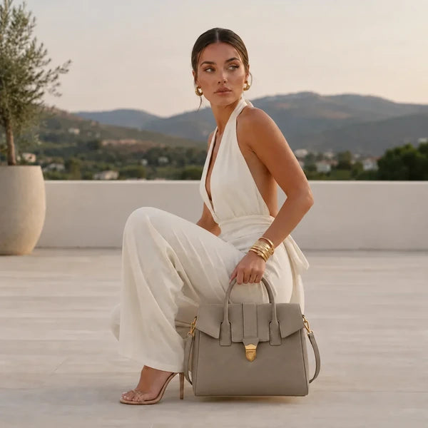 Lévoria Genuine Leather Satchel Bag in gray, held by a model in a white jumpsuit on a terrace with mountain views