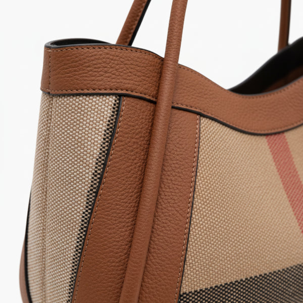 Close-up of a brown canvas and leather tote bag showcasing the textured design and leather trim