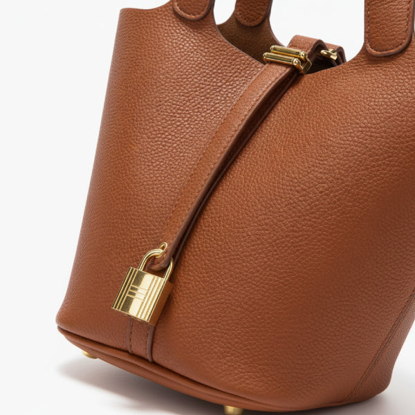 Lunelia Vegan Leather Bucket Bag in caramel, closeup highlighting pebbled texture, gold padlock detail, and structured base feet