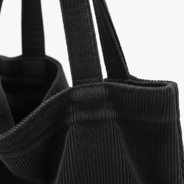 Close-up of the Marinda corduroy tote bag in black, showcasing the textured fabric and handles