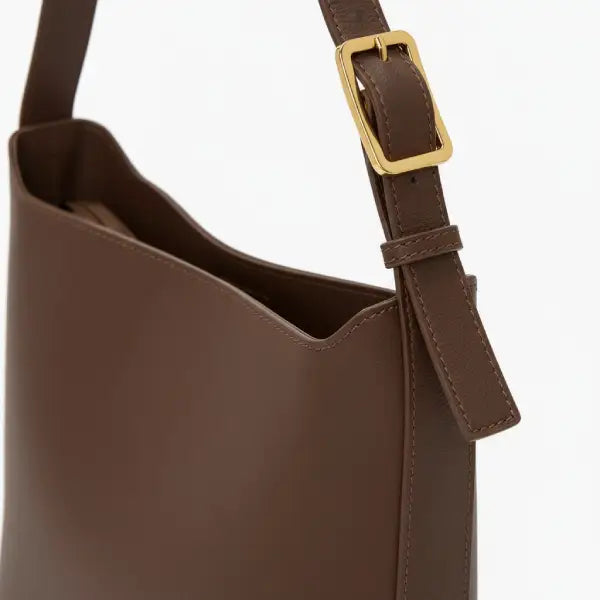 Closeup of Meliora vegan leather shoulder bag with adjustable strap and gold buckle in coffee color