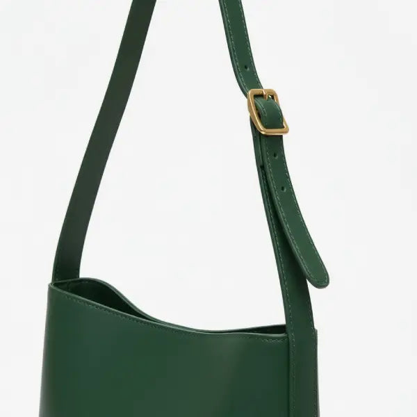 Closeup of Meliora vegan leather shoulder bag with adjustable strap and gold buckle in green color