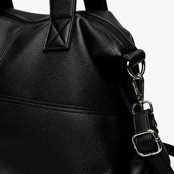 Close-up of Mirelith black leather satchel bag with quilted detailing and adjustable strap with silver hardware