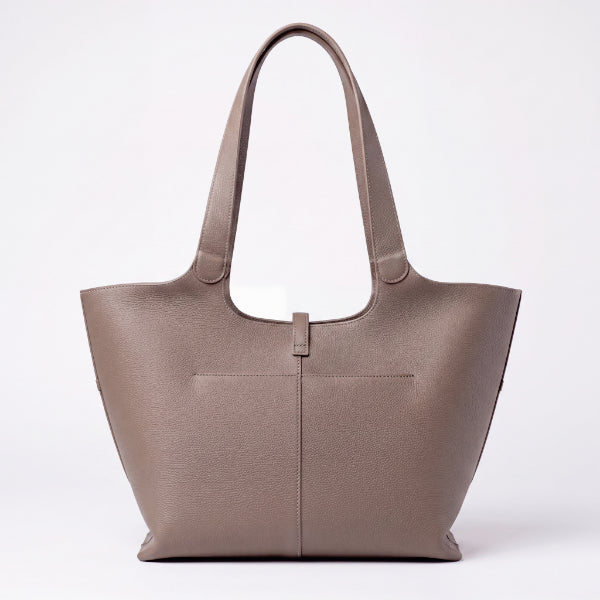 A taupe brown textured leather tote bag with double shoulder straps and a front pocket, photographed against a clean white background.