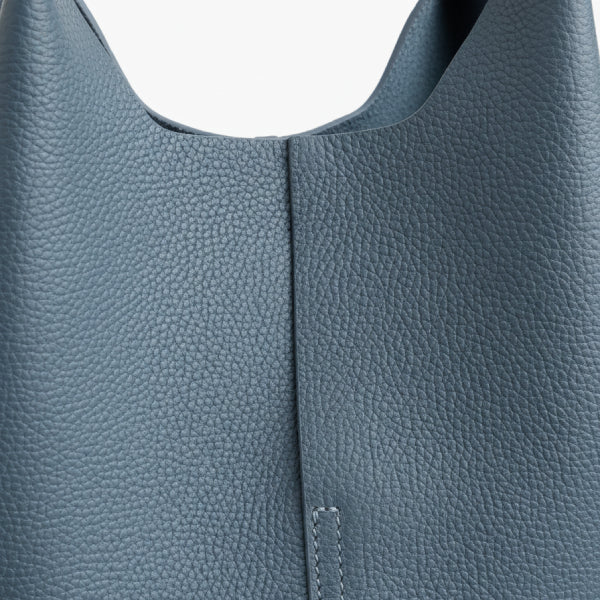 Close-up of blue cowhide leather tote bag, highlighting its textured leather and clean stitching detail for a sleek look
