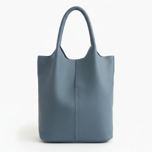 Front view of blue cowhide leather tote bag with minimalist design, featuring a central seam and sturdy handles