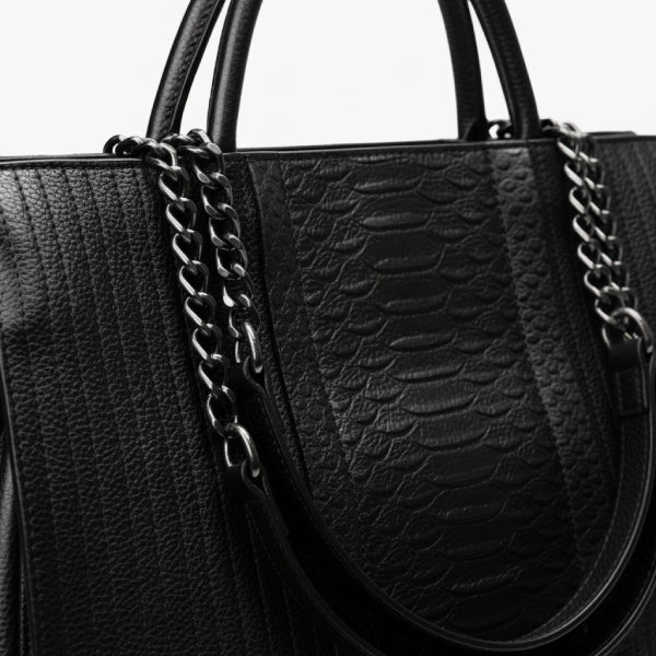 Close-up of black genuine leather tote bag, highlighting its textured leather and elegant chain handle details