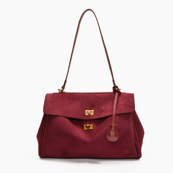 Front view of red velvet satchel bag featuring two gold clasps and a structured design