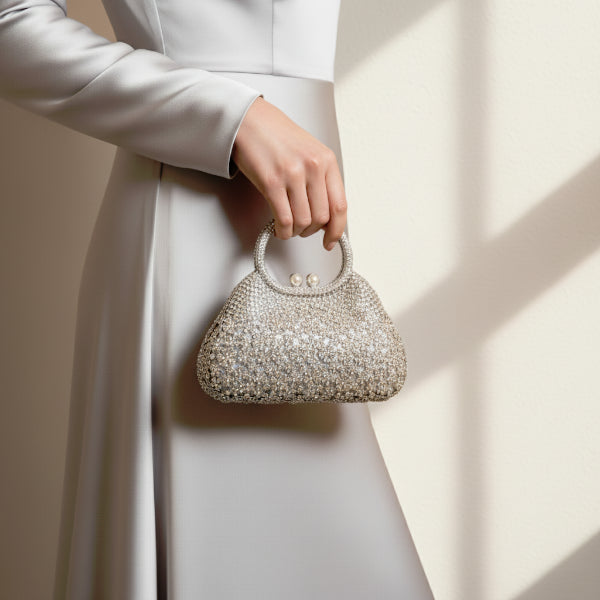 Model holding serenna rhinestone evening bag in silver with rhinestone and pearl clasp