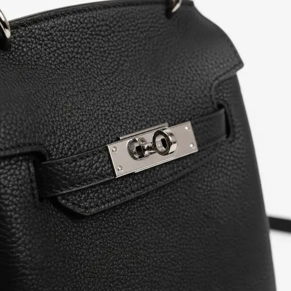 Close-up shot highlighting the silver clasp of the black genuine leather satchel bag, emphasizing the elegant design and texture of the leather