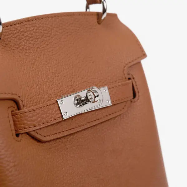 Close-up shot of the silver clasp on the brown genuine leather satchel bag, highlighting the detailed craftsmanship and soft leather texture