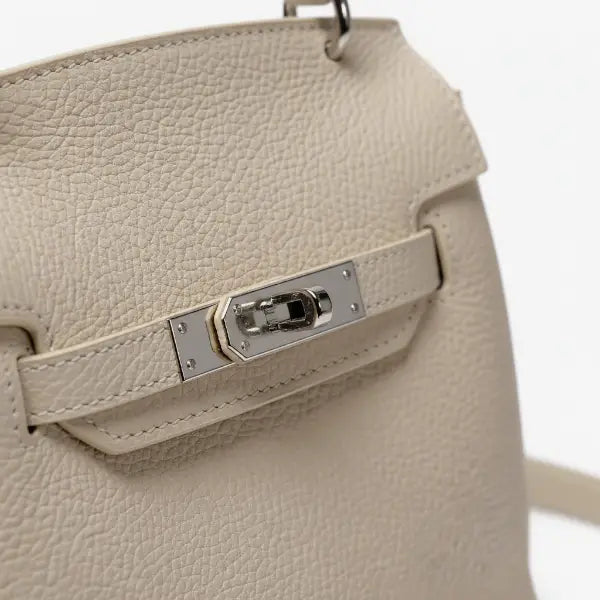Close-up shot of the silver clasp on the off-white genuine leather satchel bag, showcasing the elegant design and smooth leather texture