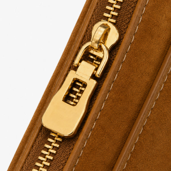 Close-up of a brown suede or microfiber pouch with a polished gold-tone zipper pull and matching gold zipper teeth, set against a light gray background.
