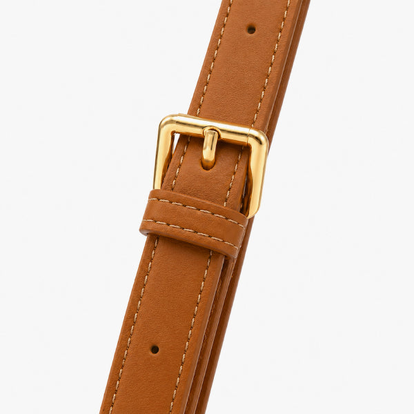 A close-up of a tan leather watch strap with a polished gold buckle, showing the stitching and adjustment holes against a light gray background.