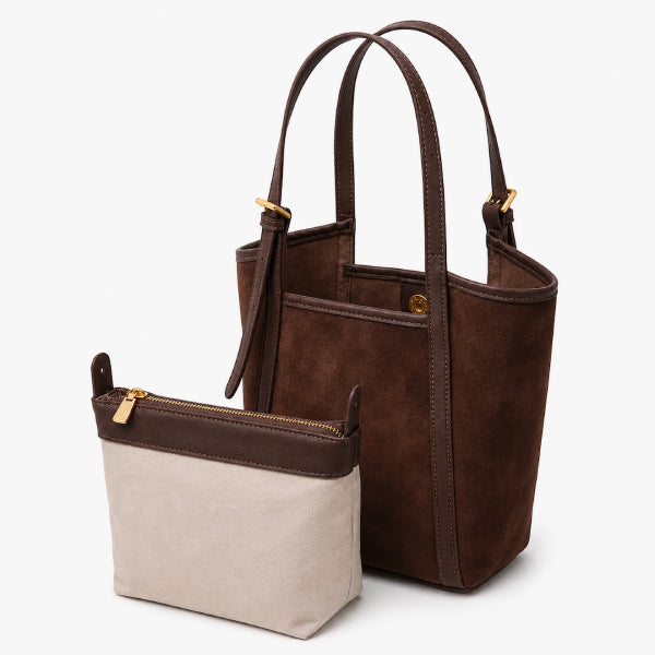 A dark brown suede tote bag with matching dark brown leather handles and trim, shown alongside a matching zippered pouch in beige and dark brown, on a light gray background.