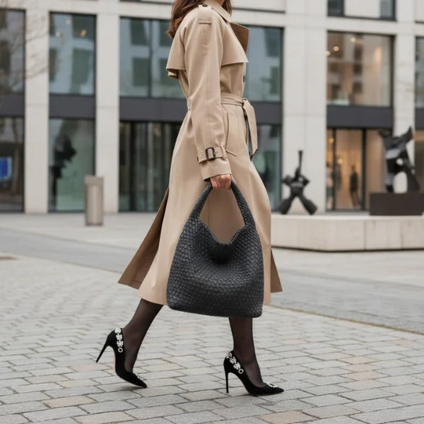 Soraya Vegan Leather Hobo Bag in dark grey, city street style with model in trench coat carrying large woven hobo for polished everyday look