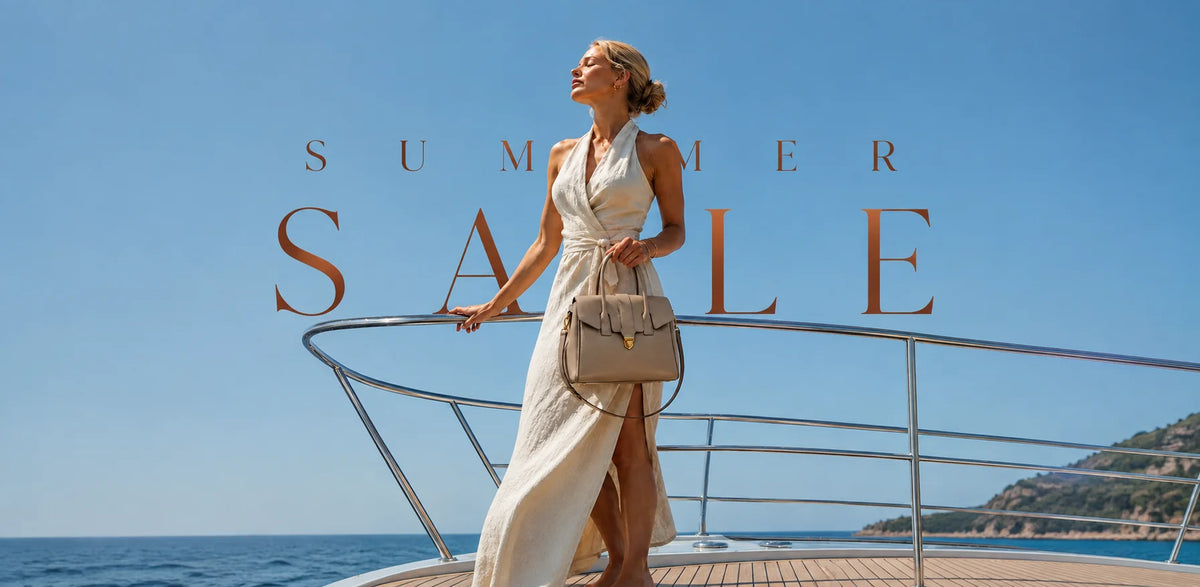 A woman in a white sleeveless maxi dress stands on the deck of a yacht holding a beige handbag, with large overlaid text reading 'SUMMER SALE' against a blue sky and sea background.