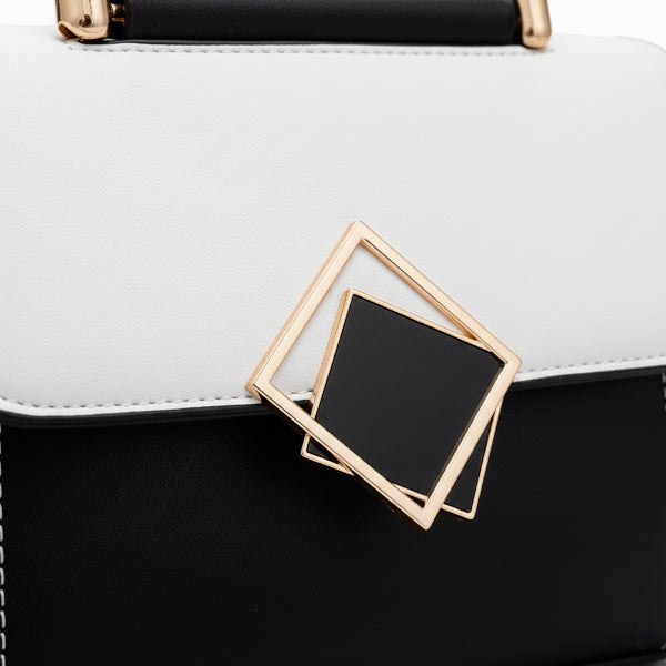Close-up of the geometric gold-tone clasp on the black and white vegan leather satchel bag, highlighting its sleek and contemporary design