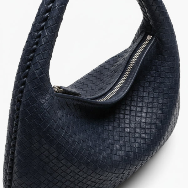 Close-up of dark blue woven vegan leather hobo bag featuring a detailed zipper closure and braided handle
