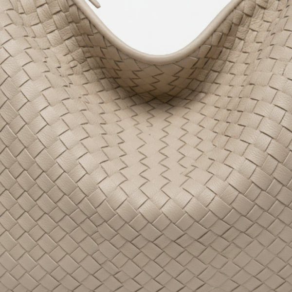 Close-up of off-white woven vegan leather hobo bag with zipper closure and smooth texture