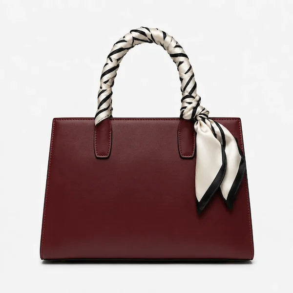 A structured burgundy leather handbag with a braided black and white handle and a matching tied scarf, shown against a plain white background.