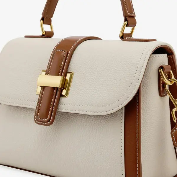 Close-up of the gold-tone clasp and brown leather detailing on the off-white genuine leather satchel bag, highlighting the premium craftsmanship