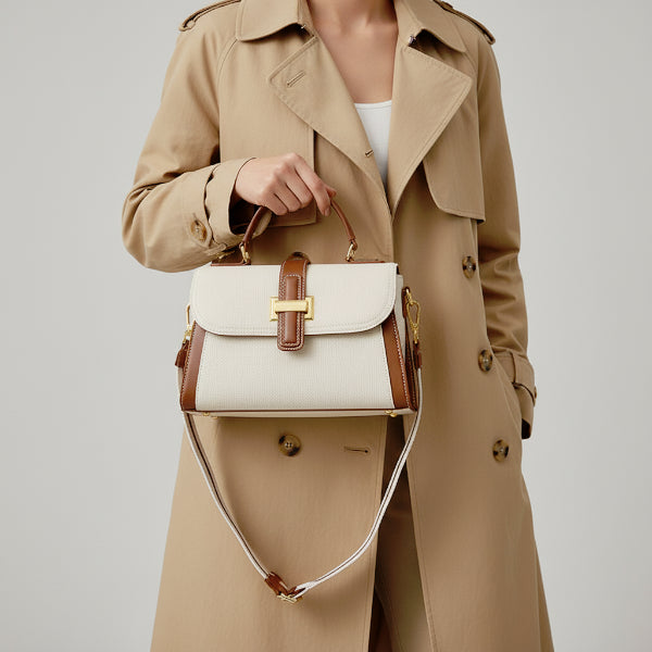 Model in a beige trench coat holding an off-white genuine leather satchel bag with brown leather trim and gold-tone hardware, perfect for an elegant, everyday look