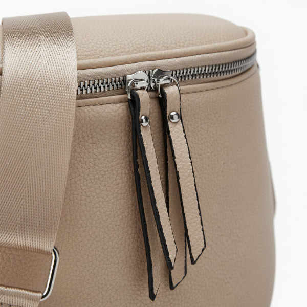 Close-up of an apricot vegan leather crossbody bag showing the zipper detail with matching zipper pulls and strap attachment