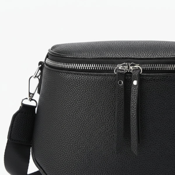 Close-up of the black vegan leather crossbody bag with zipper details and matching black strap