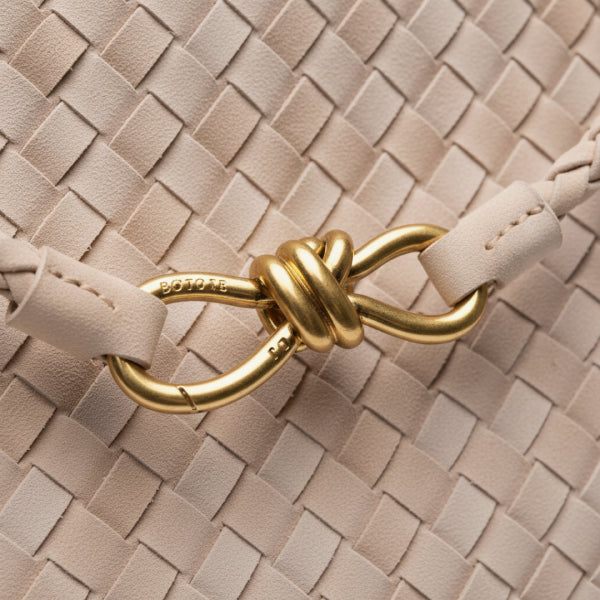Close-up of the Veyra vegan leather tote bag in beige, highlighting the elegant braided leather strap and gold-tone knot closure