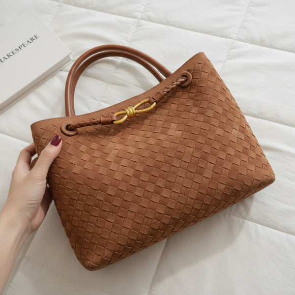 Close-up of the Veyra vegan leather tote bag in brown, held by a hand, showcasing its woven texture and gold-tone knot closure