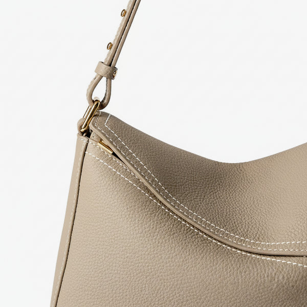 Close-up of Virella beige leather hobo bag featuring gold zipper, fine texture, and white stitching details