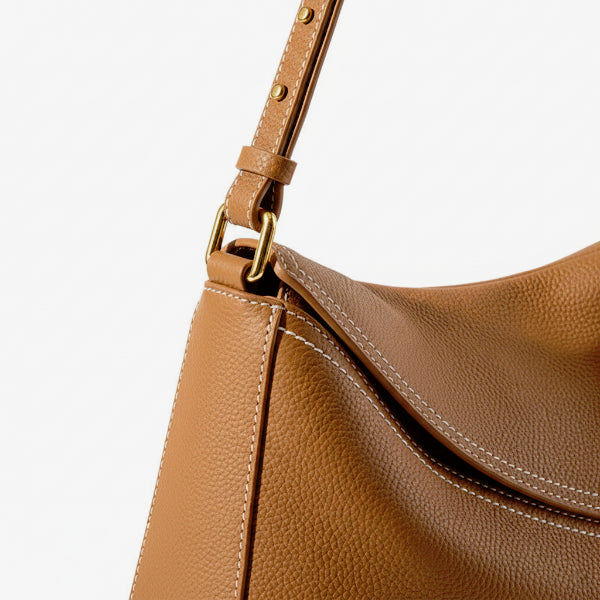 Close-up of Virella brown leather hobo bag with gold hardware and white stitching detail