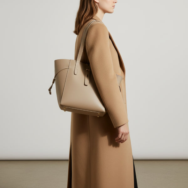 Model wearing a beige coat, carrying the khaki Zairen genuine cowhide tote bag in an indoor setting